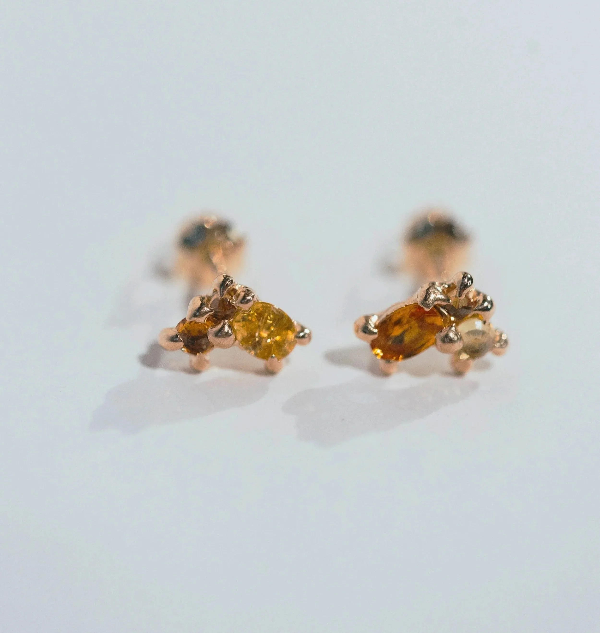 Pair of gold stud earrings with amber-colored gemstones on a white background.