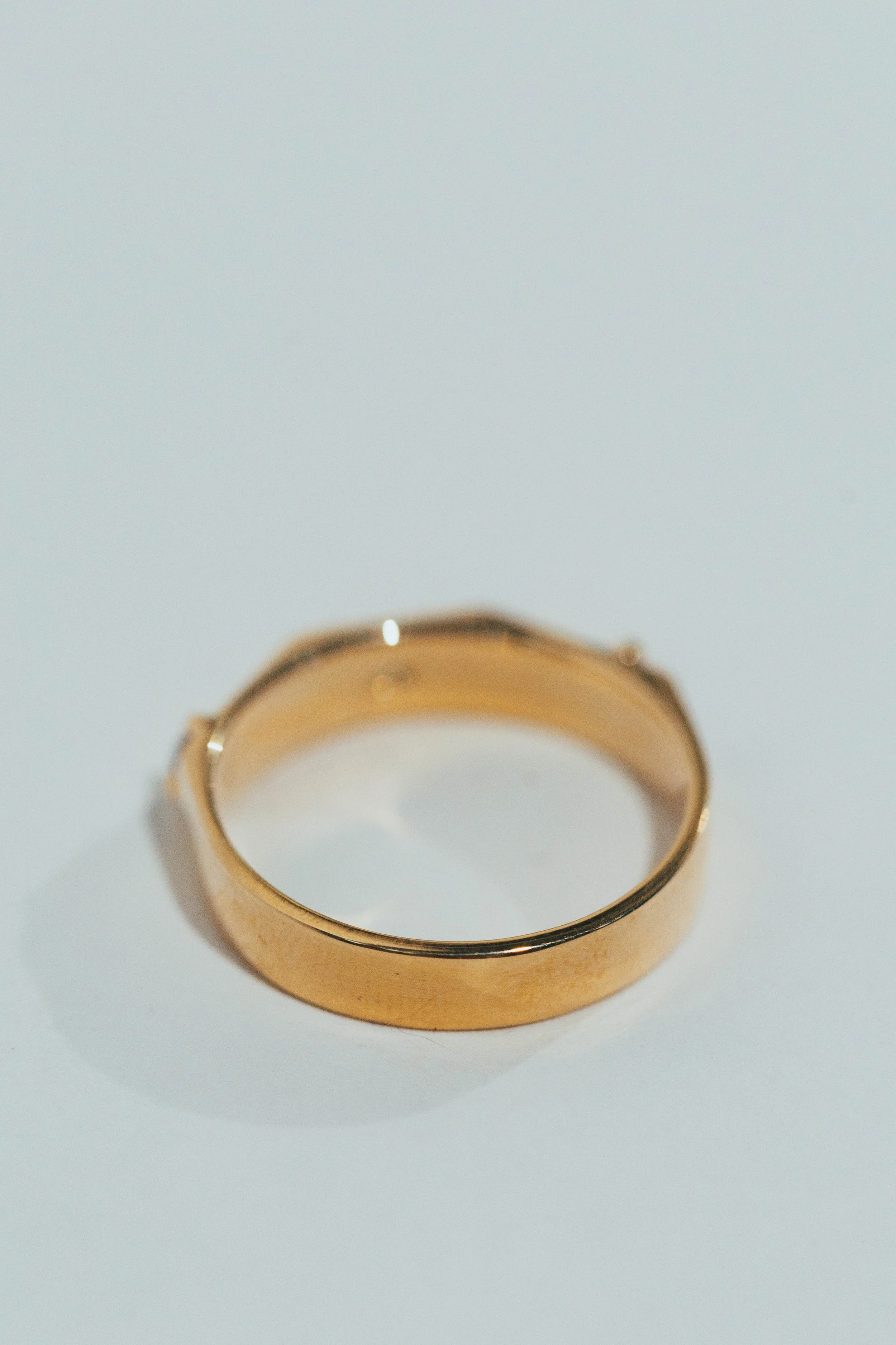 Close-up of a gold ring resting on a white surface.