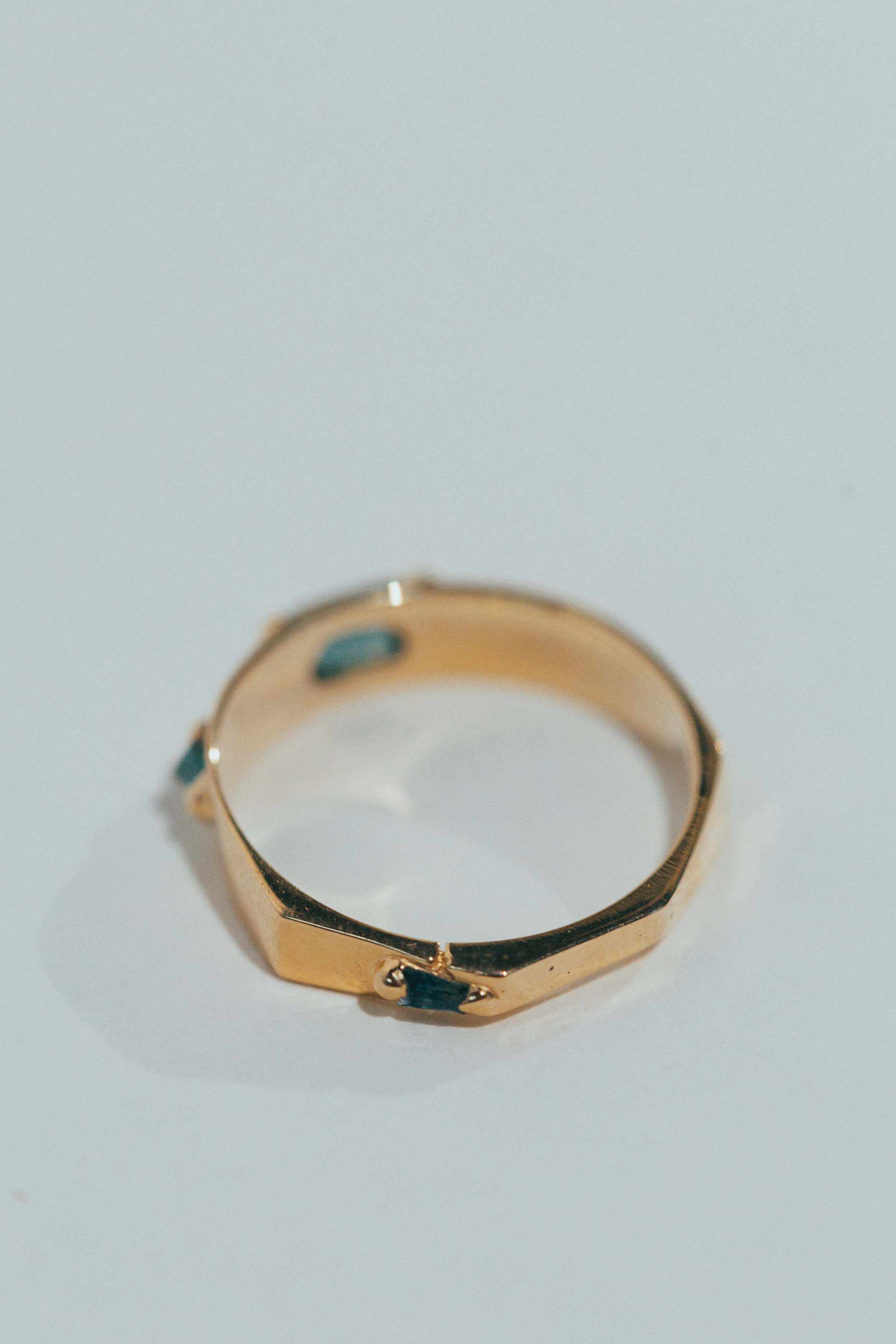 A gold ring with small blue gemstones on a plain white background.