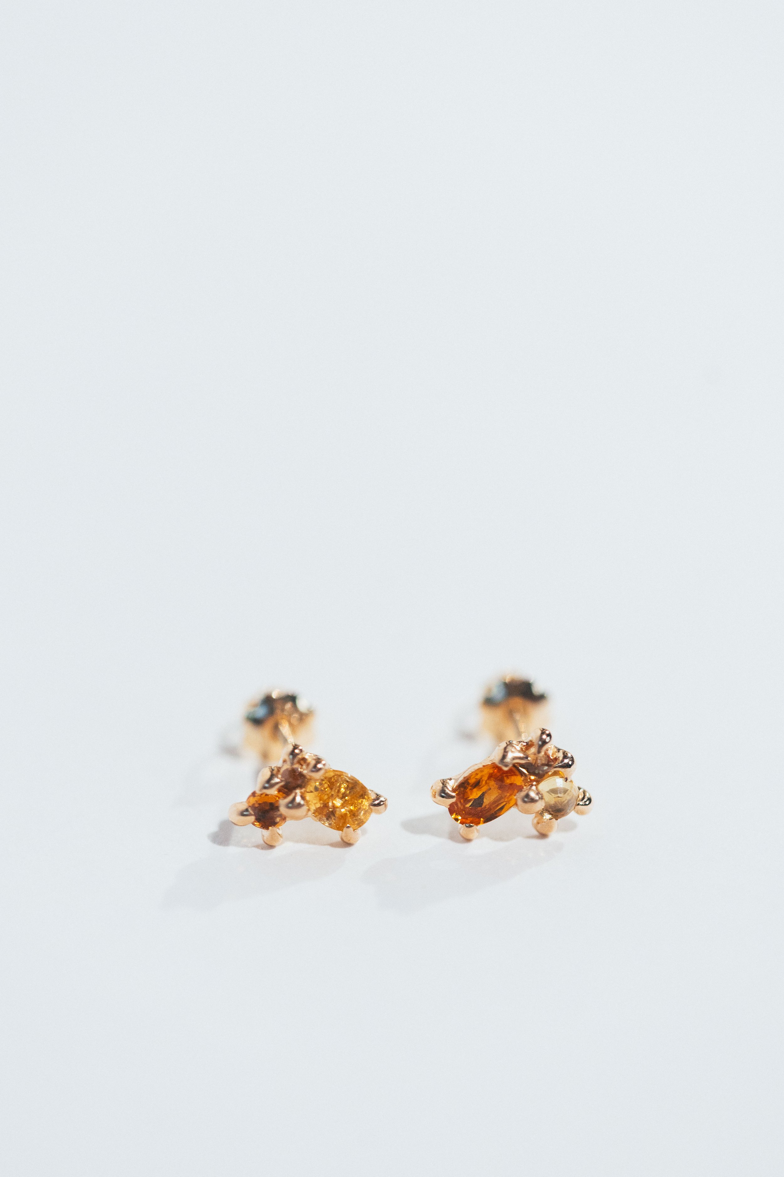 Pair of gold stud earrings with amber gemstones on a white surface.