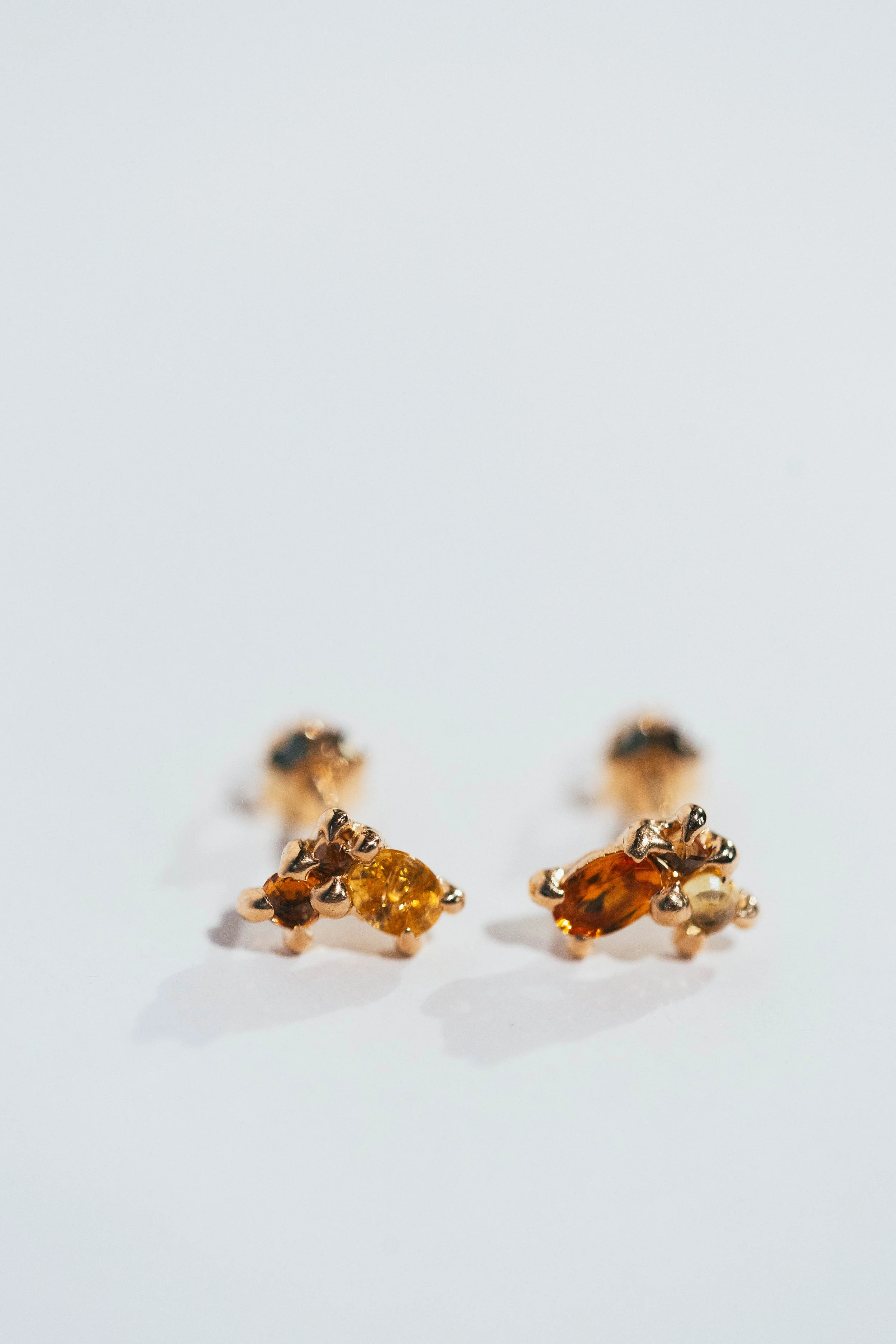 Gold earrings with amber and yellow gemstones on a white background.