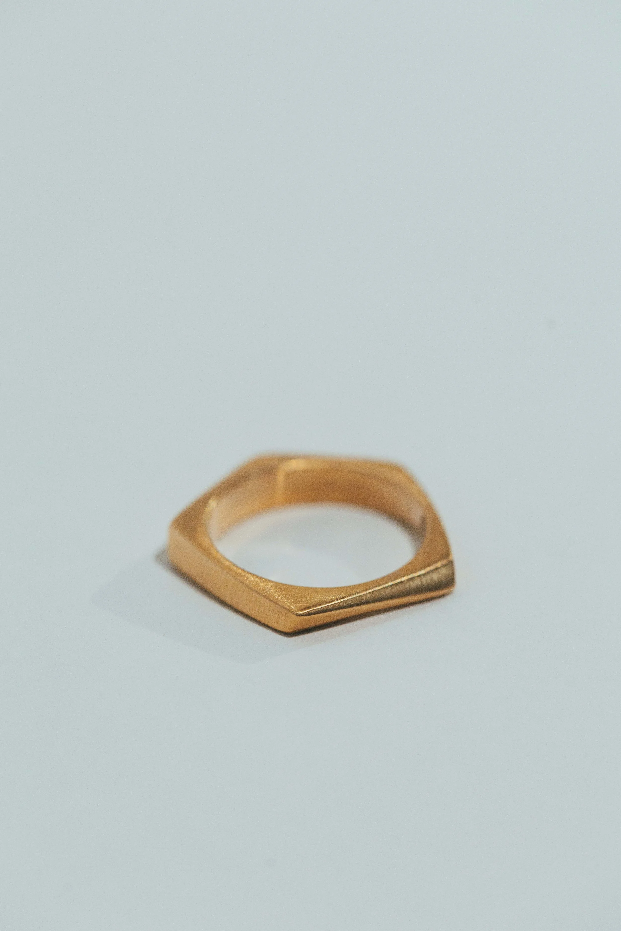A gold geometric-shaped ring on a white background.