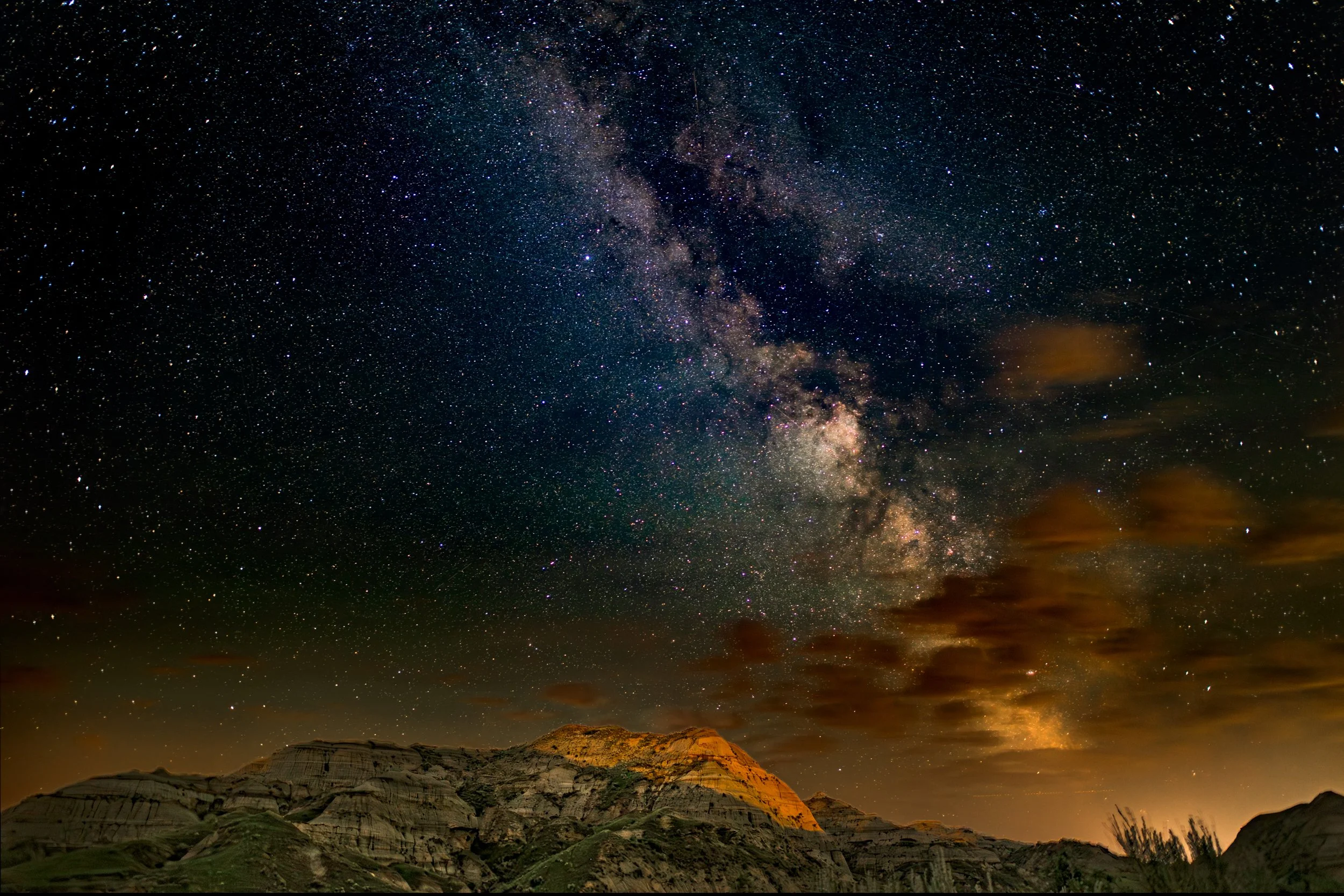 Night sky filled with stars and the Milky Way galaxy over rugged mountains.