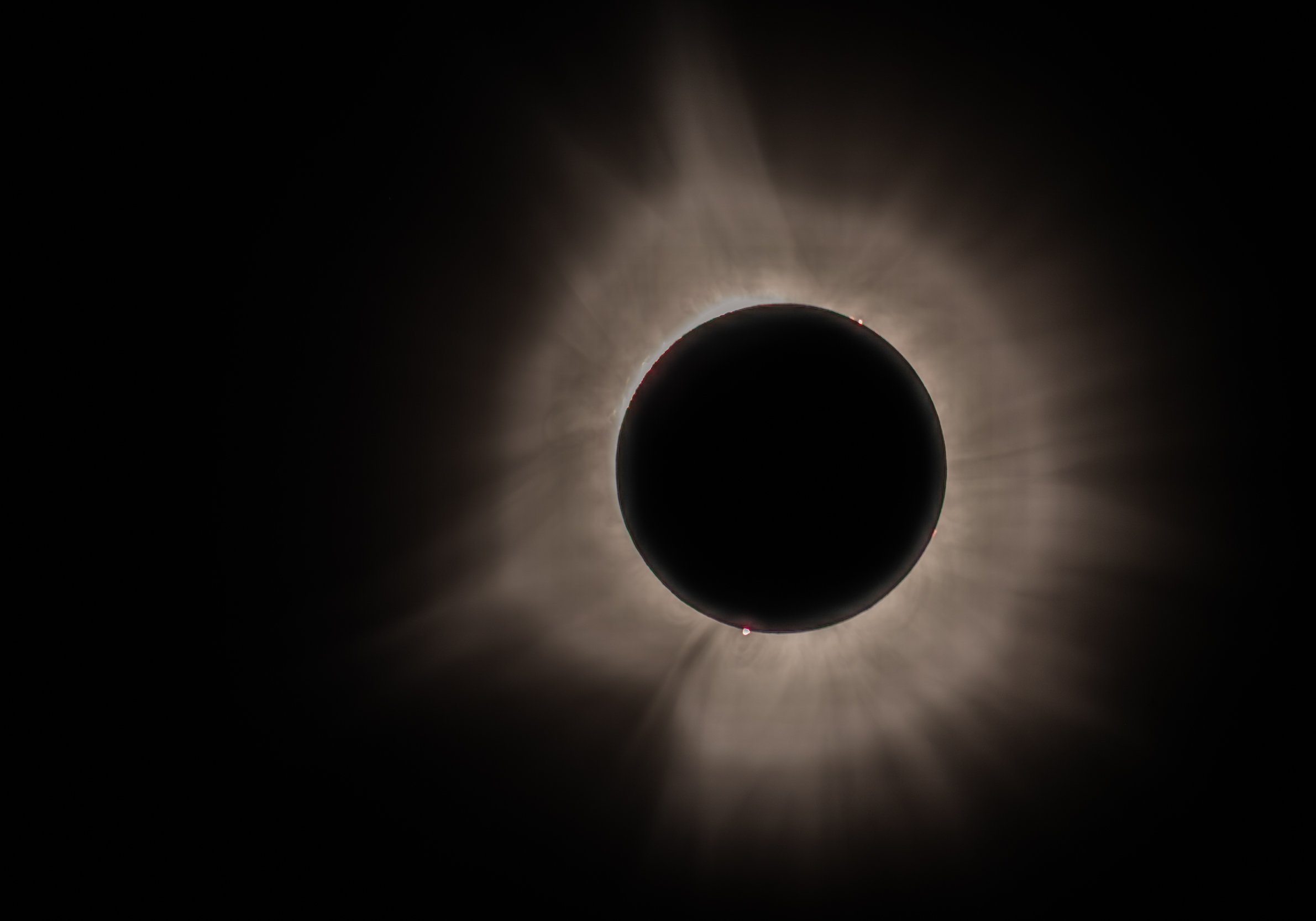 A solar eclipse with the moon blocking the sun, creating a dark circle with bright rays of light radiating outward.