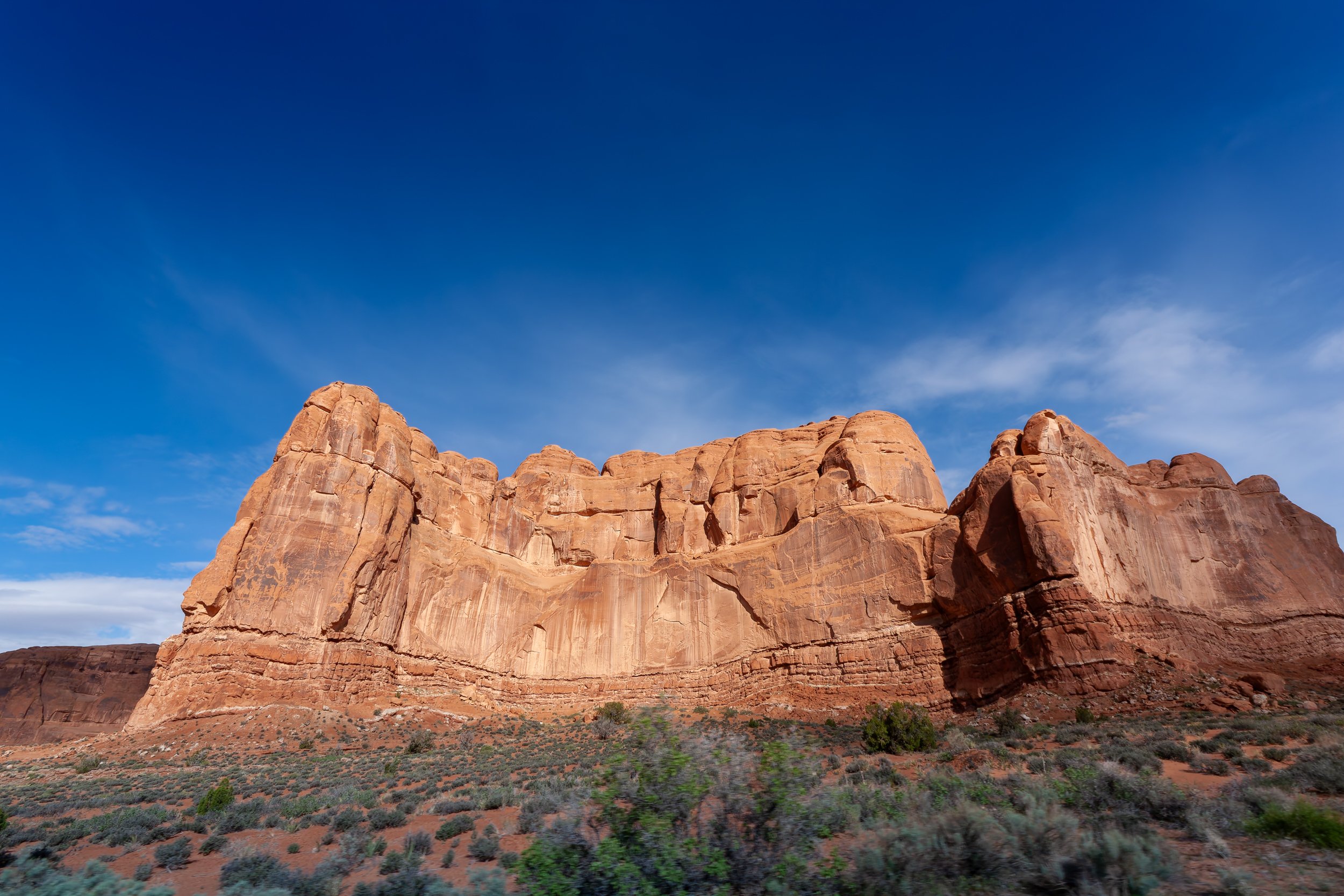 Red rock formations in a desert landscape under a blue sky with some clouds.