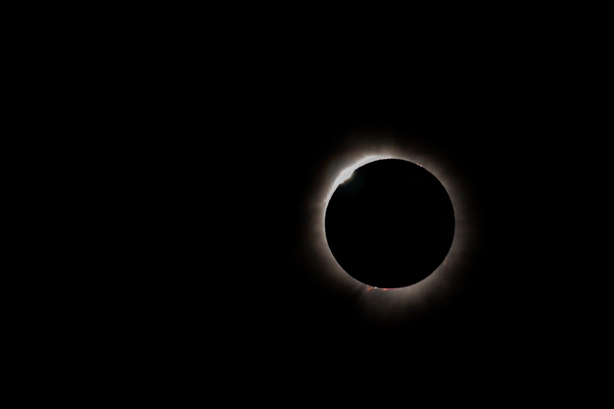 A solar eclipse with the moon blocking the sun, leaving a bright ring of light around the darkened sun.