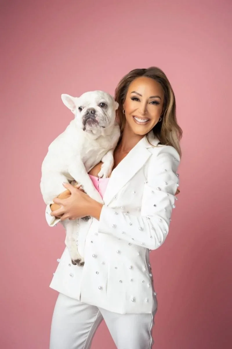 Women in business photoshoot with a pink background and a white bulldog.