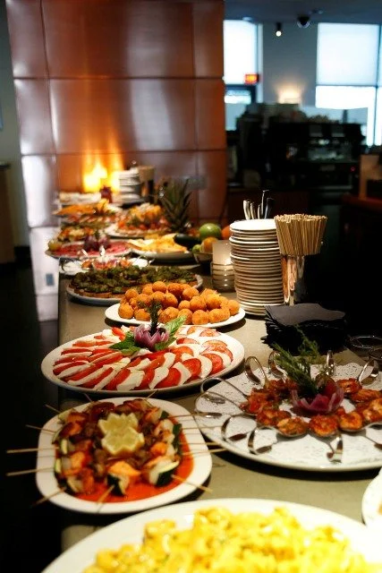 Buffet table with various dishes including sushi, fried foods, salads, and appetizers in a restaurant setting.