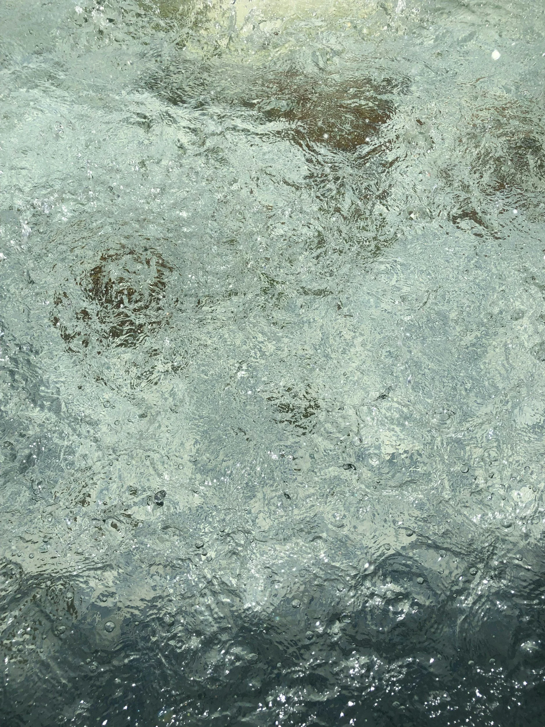 Close-up of bubbling water surface with ripples and bubbles.
