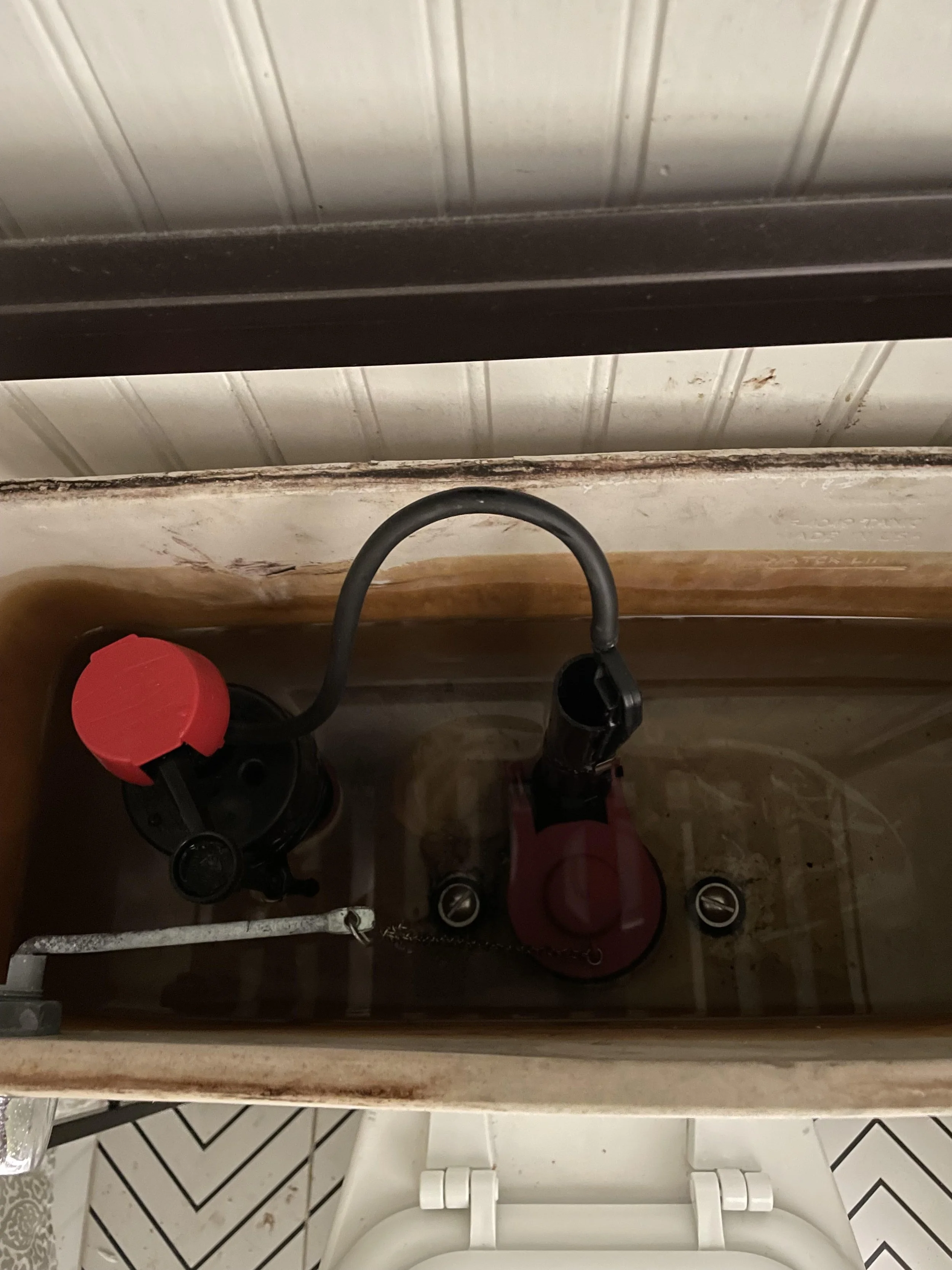 Open toilet tank with water supply valve and fill valve visible inside.