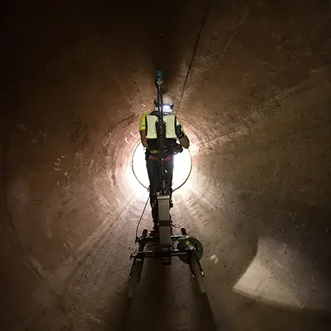 Person analyzing data on a MacBook Pro laptop, showing colorful line graphs on the screen, in a conference room with blurred background.