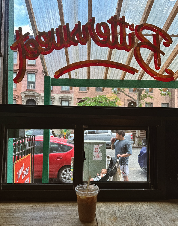 View from inside of store looking out with iced coffee on table