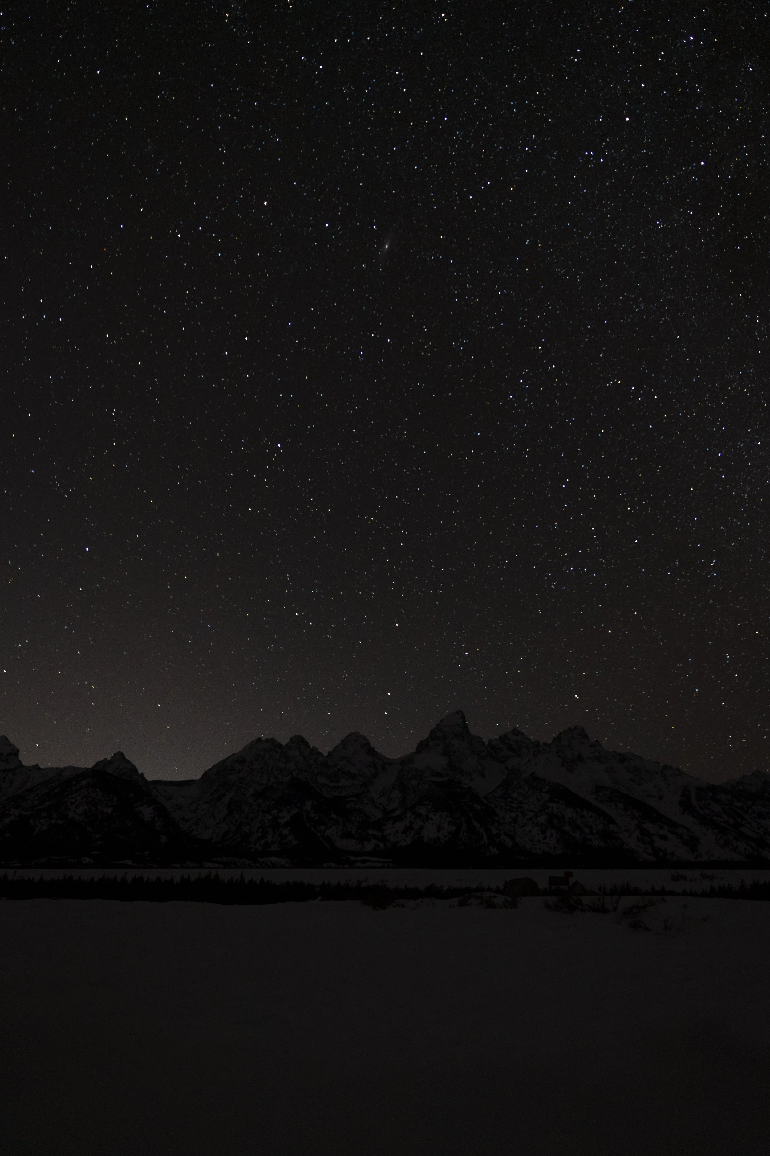 A night sky filled with stars over a silhouette of mountain peaks.