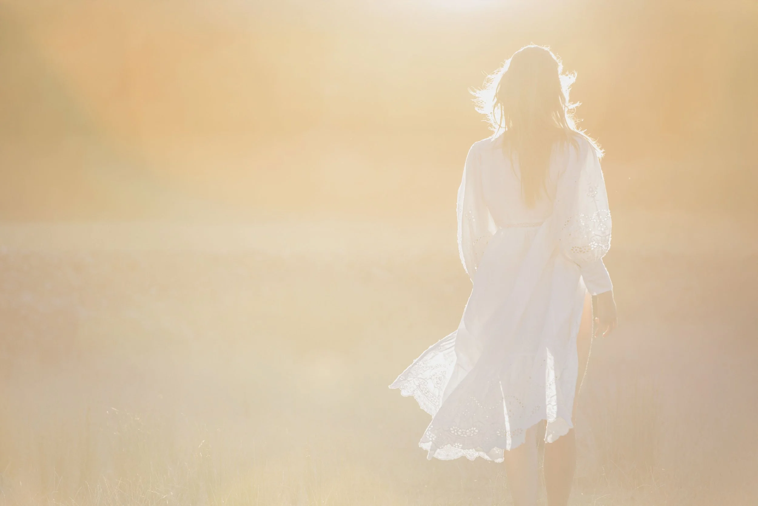 Silhouette féminine dans une lumière surexposée et solaire évoquant une sensation de liberté et d’intemporalité.