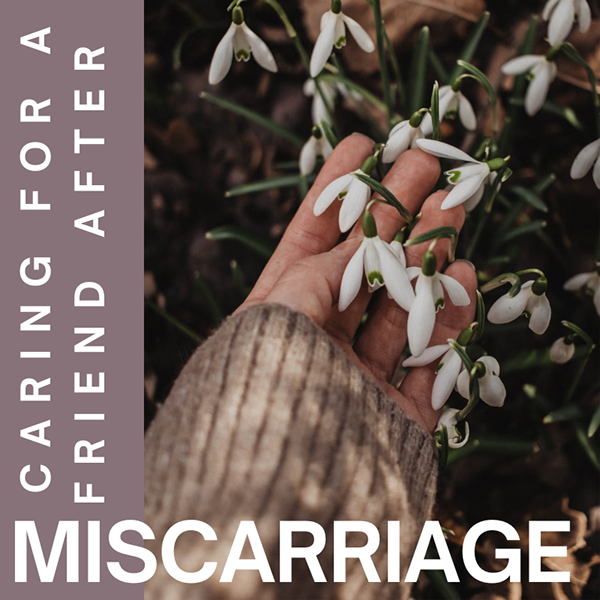 Person's hand holding snowdrop flowers outside in early spring.