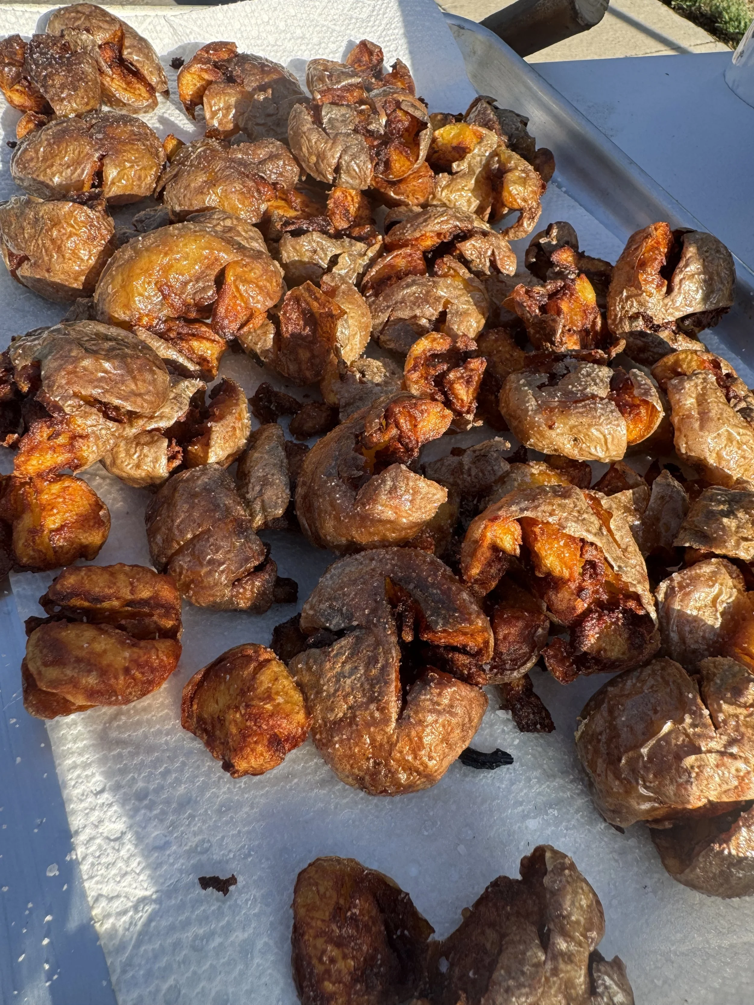 Various roasted chestnuts on a white paper-lined tray outdoors