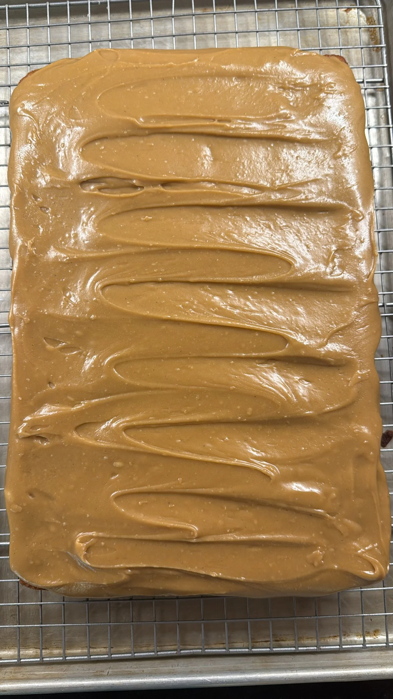 A rectangular pan of layered caramel fudge with a smooth, glossy surface and some decorative swirls on top.