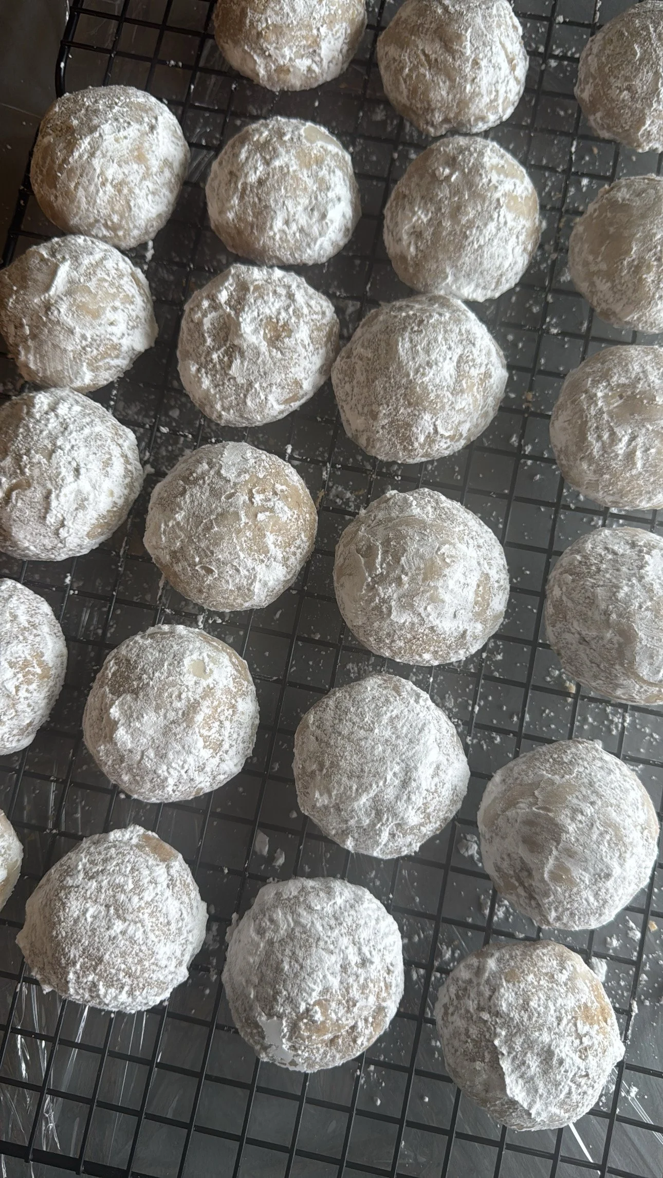 Round cookie dough balls dusted with flour arranged on a cooling rack.