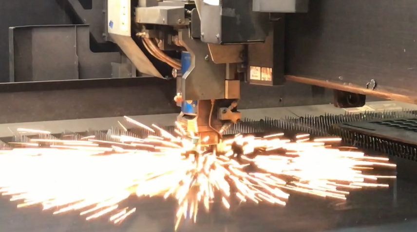 Industrial laser cutting machine in operation with sparks flying as it cuts through metal.