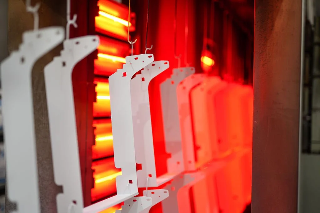 Multiple white plastic brackets hanging in front of red and orange neon lights on a display board.