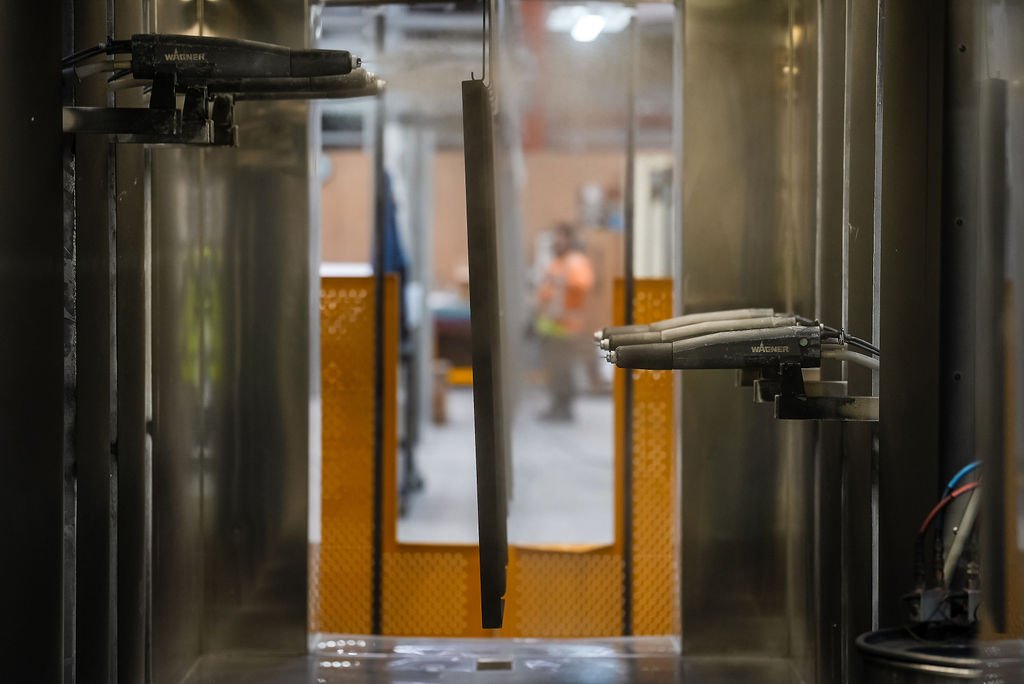 View through an elevator door showing martial art swords hanging on the door and a person wearing an orange shirt in the background.