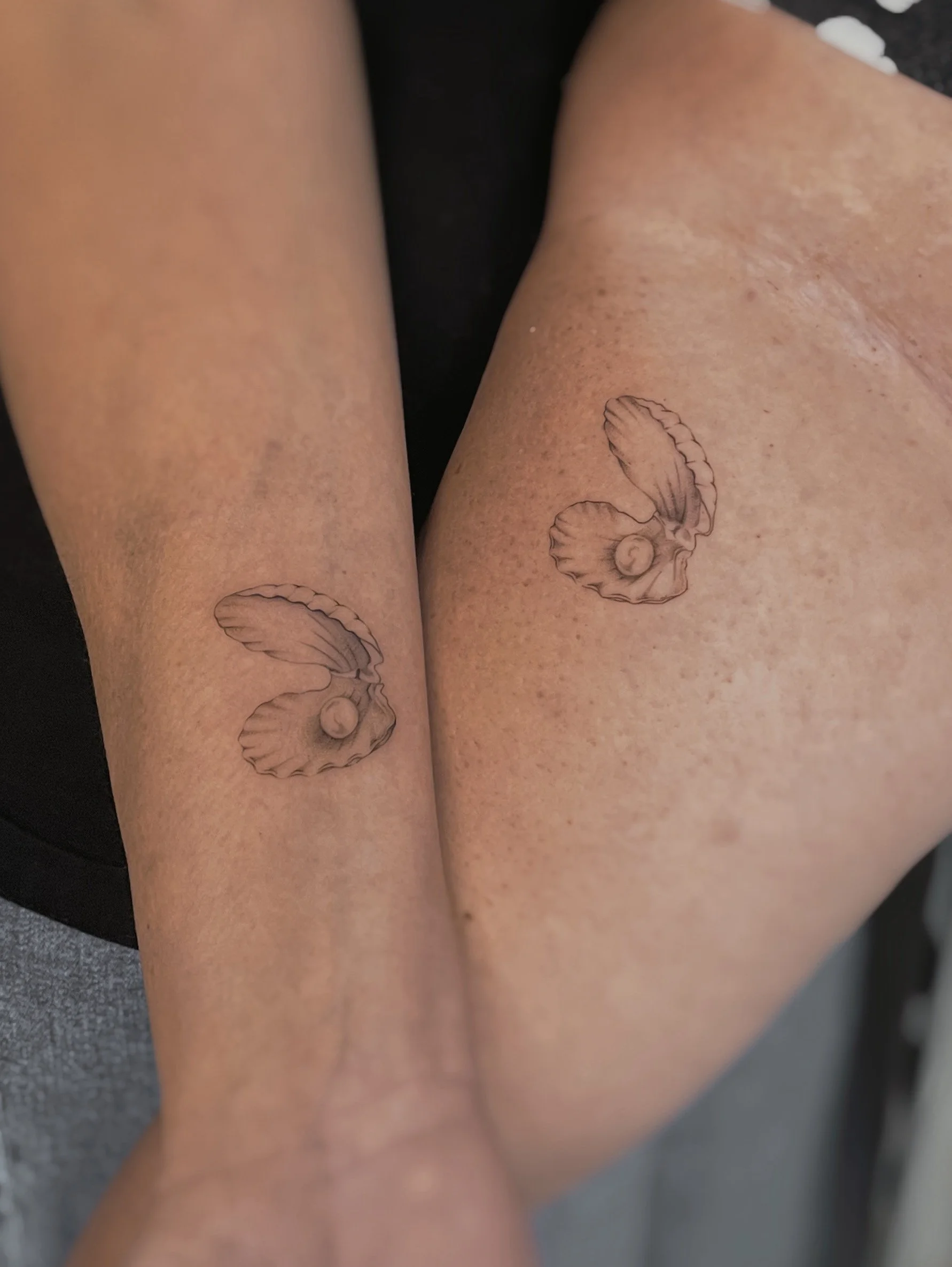 A microrealsim clam and pearl tattoo on the arm..