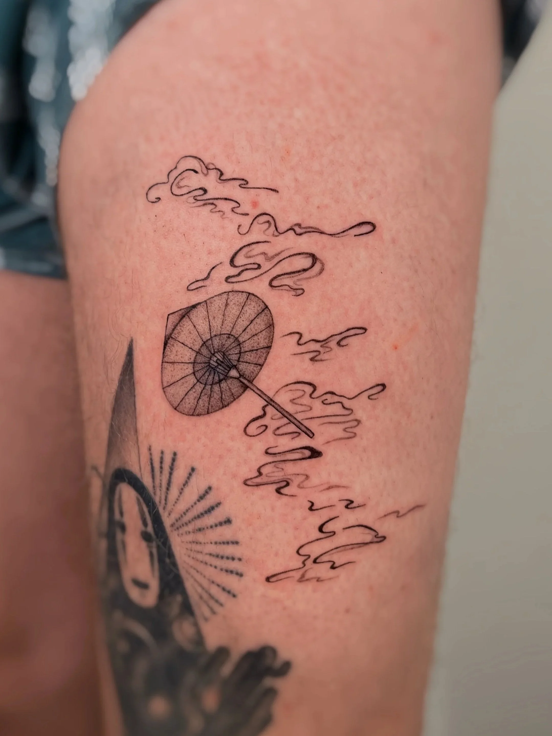 A japanese paper fan tattoo floating through clouds on the leg.