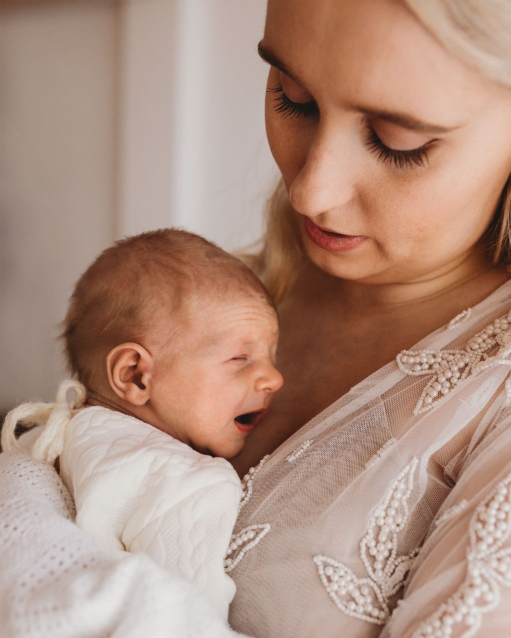 A woman holding a crying baby close to her chest, comforting him.