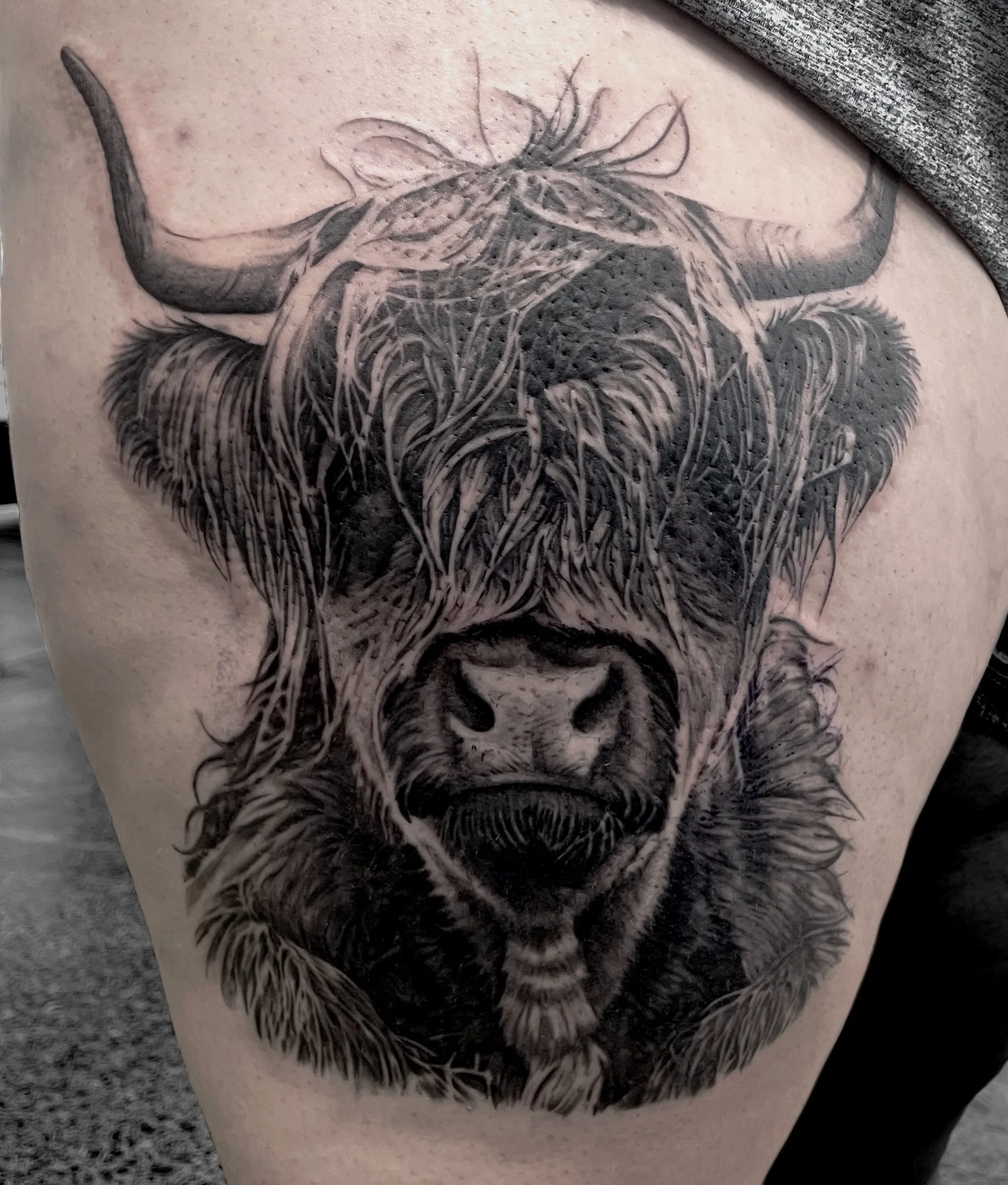 Black and gray tattoo of a bear's face on someone's thigh, featuring detailed fur and shading.