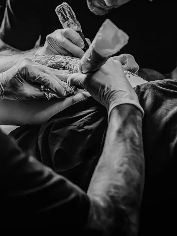 Black and white photo of a person getting a tattoo.
