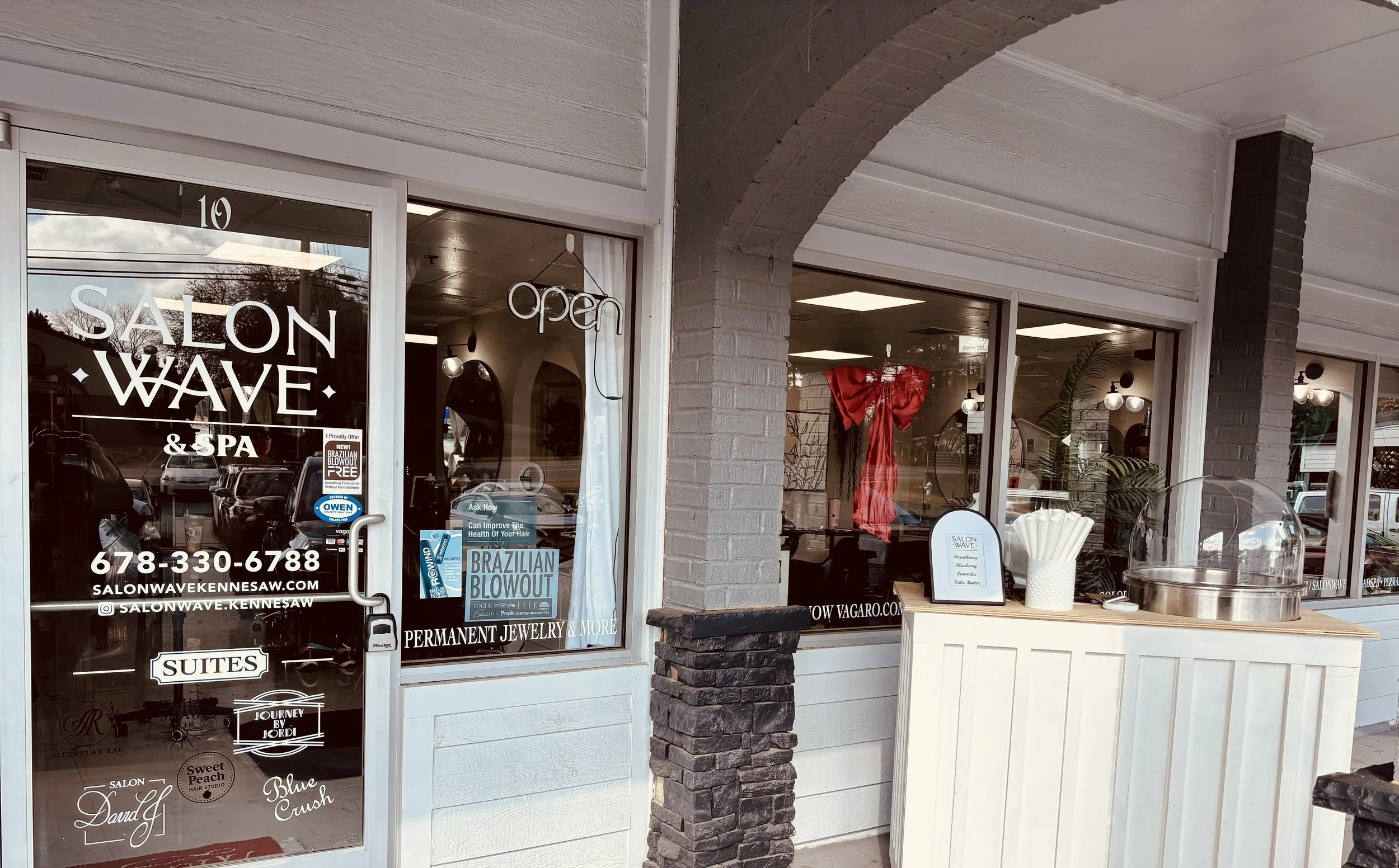 Exterior of Salon Wave & Spa with glass door and window, displaying salon services, signs, and decorations inside.