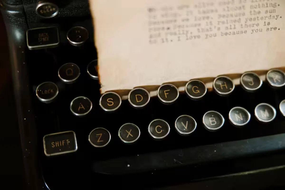 Close-up of vintage typewriter keys with a sheet of paper containing typed text on top.