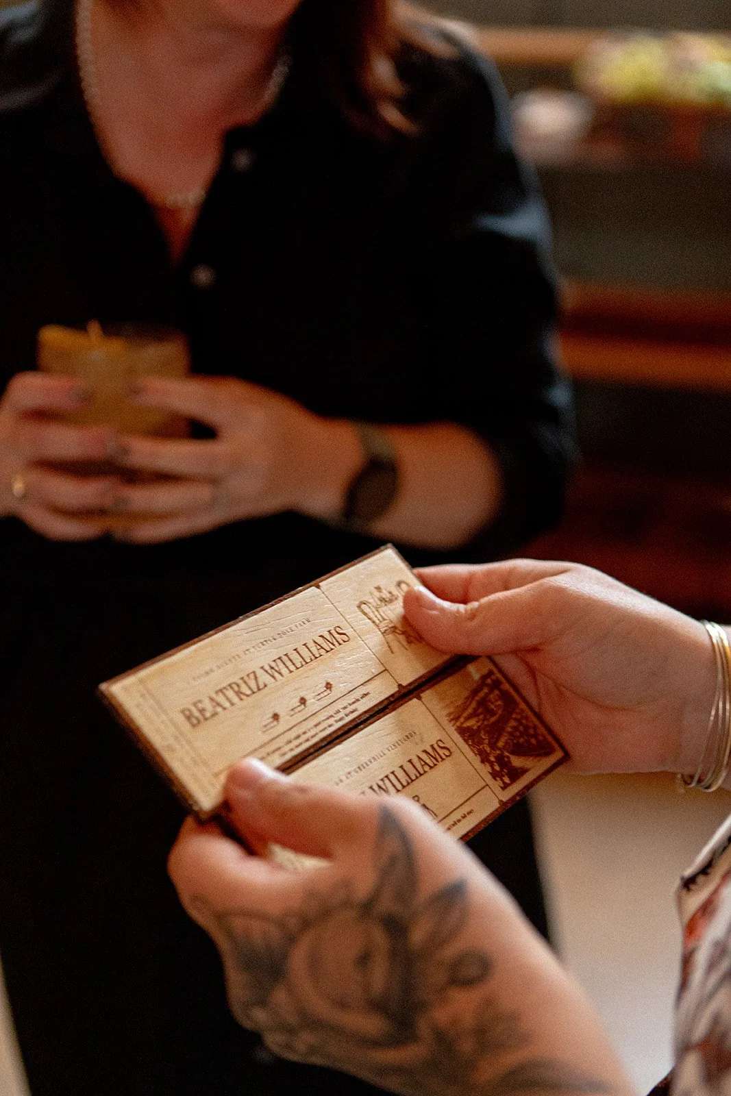 Person holding a vintage ticket that reads Beatriz Williams, with another person in the background holding a similar ticket, possibly at a book signing or event.