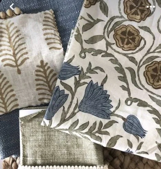 Close-up of various patterned fabrics with floral and leaf designs in neutral and blue tones.