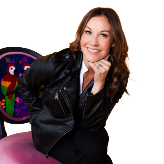 Smiling woman with wavy brown hair wearing a black leather jacket, sitting on a pink chair with a white background.