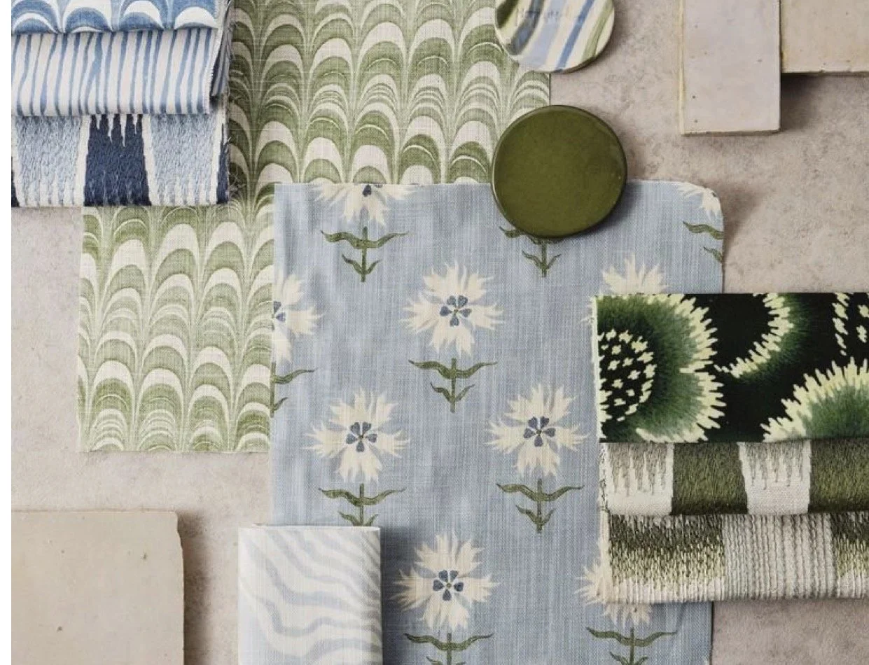A collection of various fabric swatches and a round green object on a light surface, featuring patterns of floral, geometric, and abstract designs in shades of blue, green, white, and black.