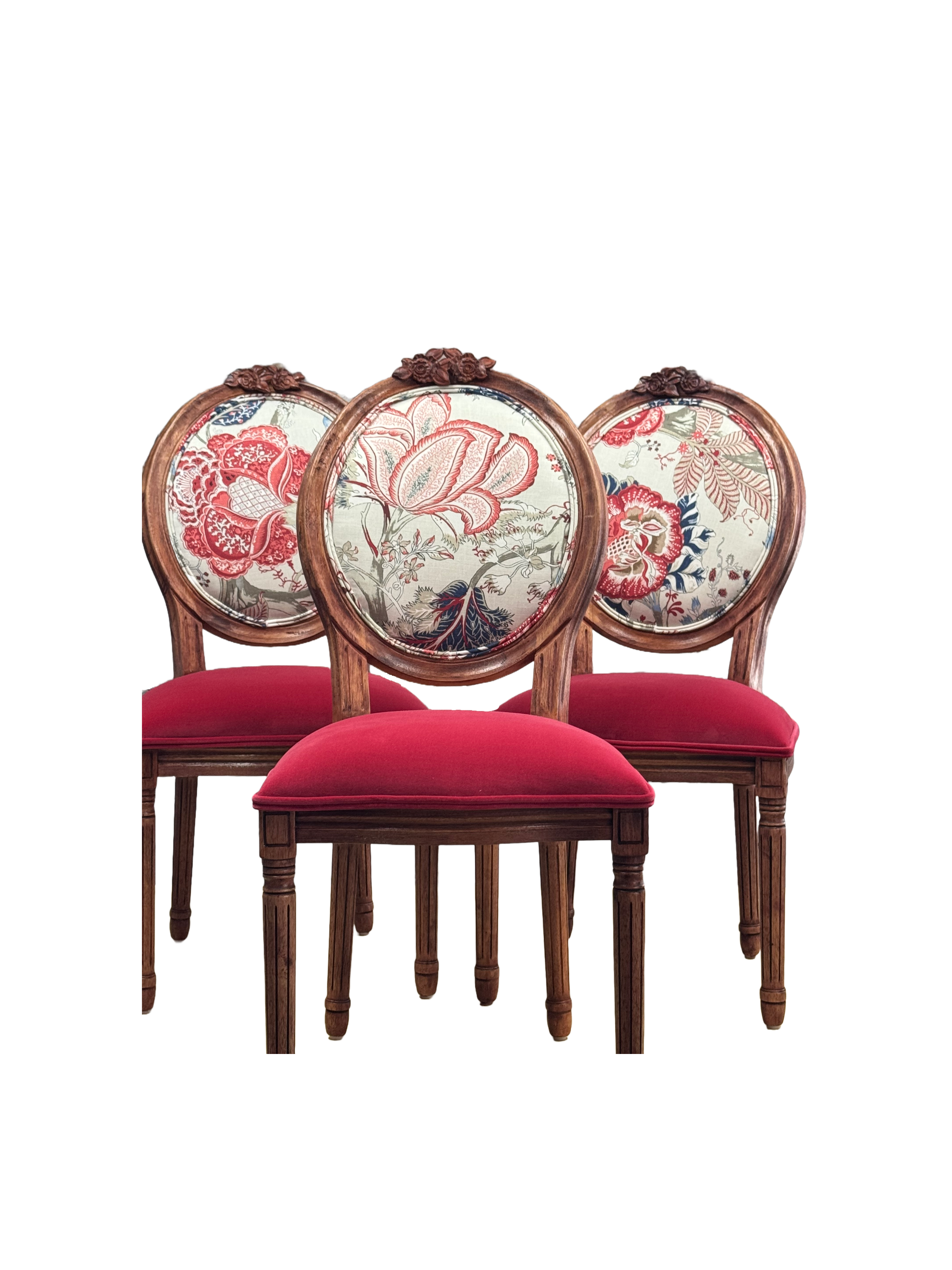 Three vintage wooden chairs with red velvet seats and floral-patterned oval backs, arranged in a row.