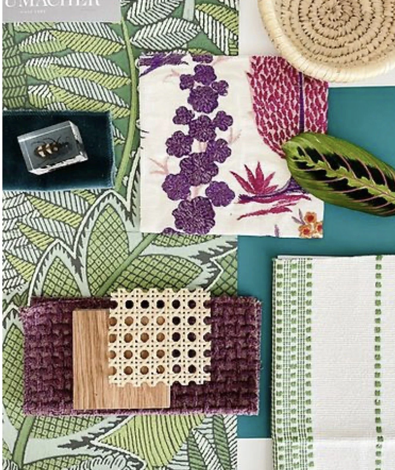 Collection of various fabric swatches with different patterns and textures, placed on a leafy green background with a striped pattern. Some swatches include floral and geometric designs, with a small jewelry box and a large leaf included in the arran