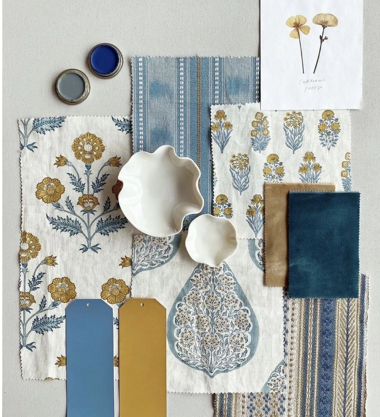 Fabric swatches, ceramic bowls, paint chips, and botanical illustrations for interior design planning.