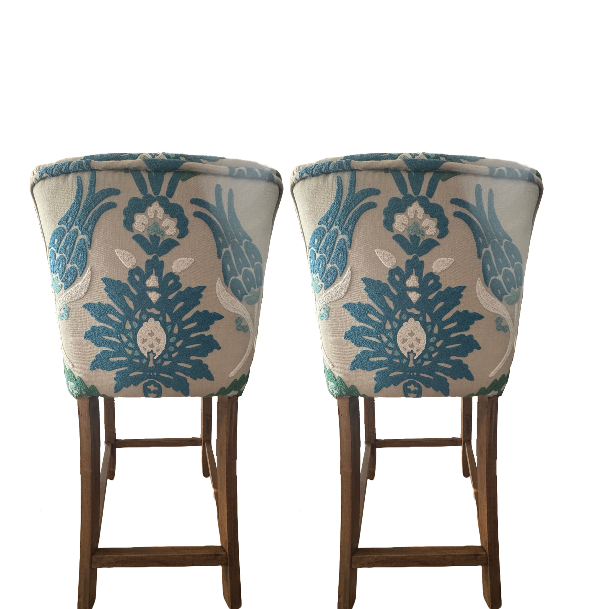 Two upholstered chairs with floral and leaf patterns on fabric, wooden legs, against a white background.