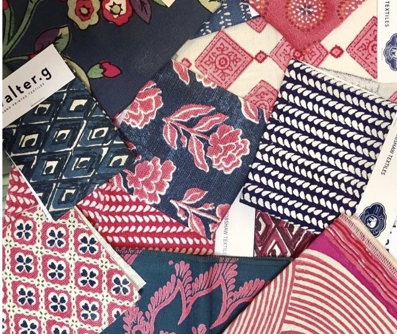 A collection of fabric swatches with various patterns and colors, including floral, geometric, and striped designs, displayed together.