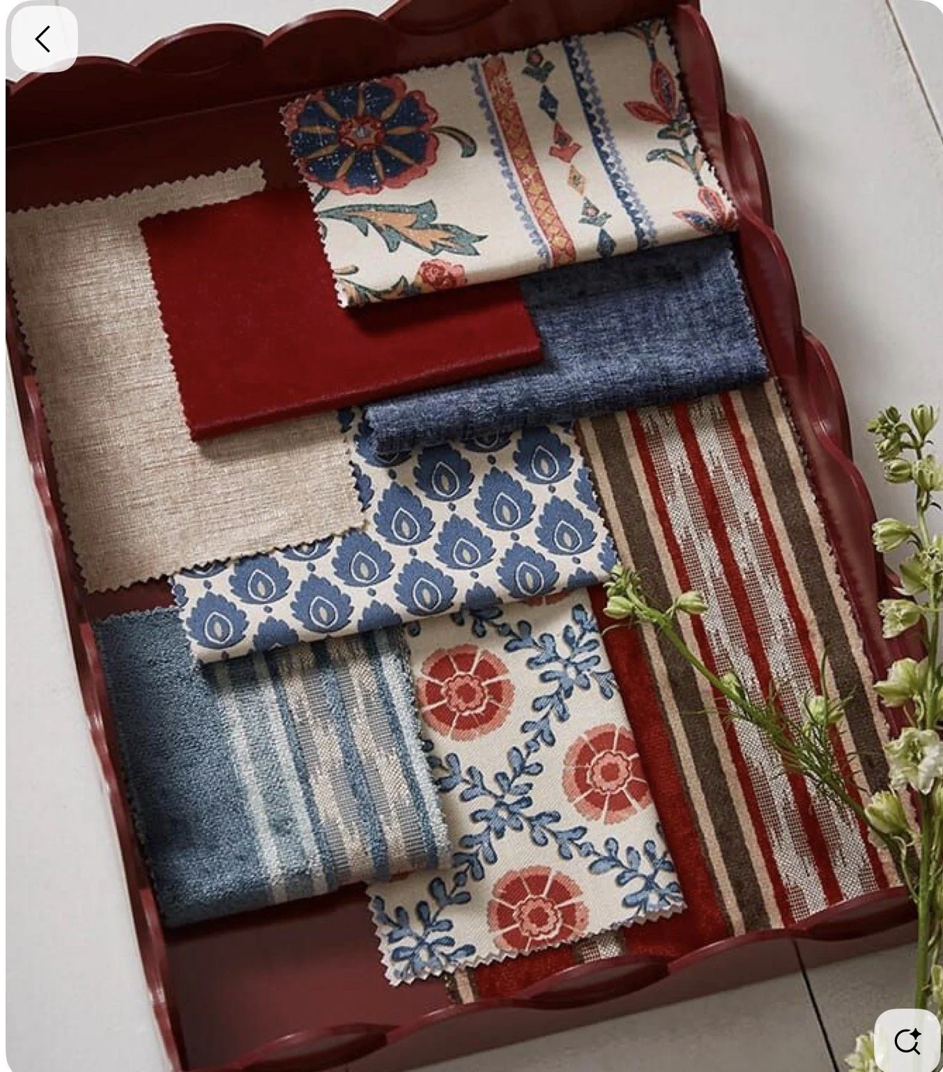 A red tray holding various fabric swatches with different patterns and colors, including floral, striped, and geometric designs.
