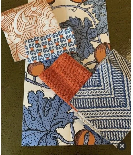 A patchwork fabric arrangement with various textile patterns and a knitting sampler placed on top.