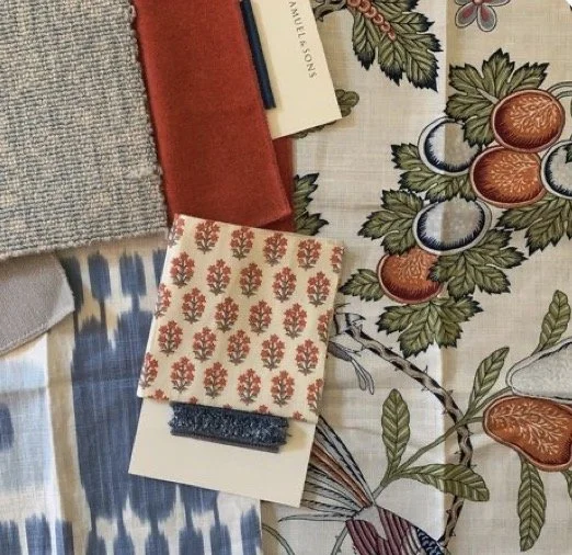 A table setting with patterned cloth, a red book, a small floral decorative object, and various papers or napkins.