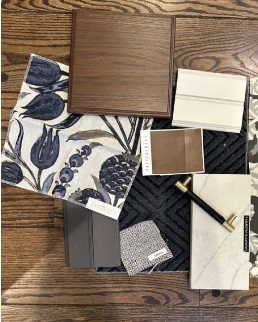 Interior design samples including fabric swatches, tiles, and material samples displayed on a wooden surface.