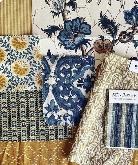 A collection of fabric and wallpaper samples featuring floral and leaf patterns in blue, yellow, black, and white colors.