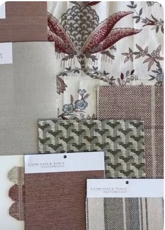 A collection of fabric swatches and wallpaper samples, including floral, geometric, and striped patterns, displayed on a flat surface.