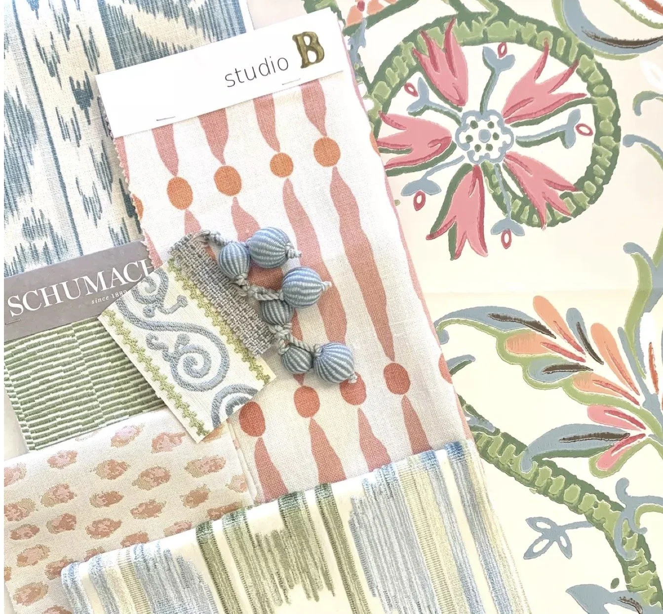 Display of fabric swatches with various patterns and colors, including stripes, florals, and abstract designs, along with a label 'studio B' and a decorative bead embellishment.