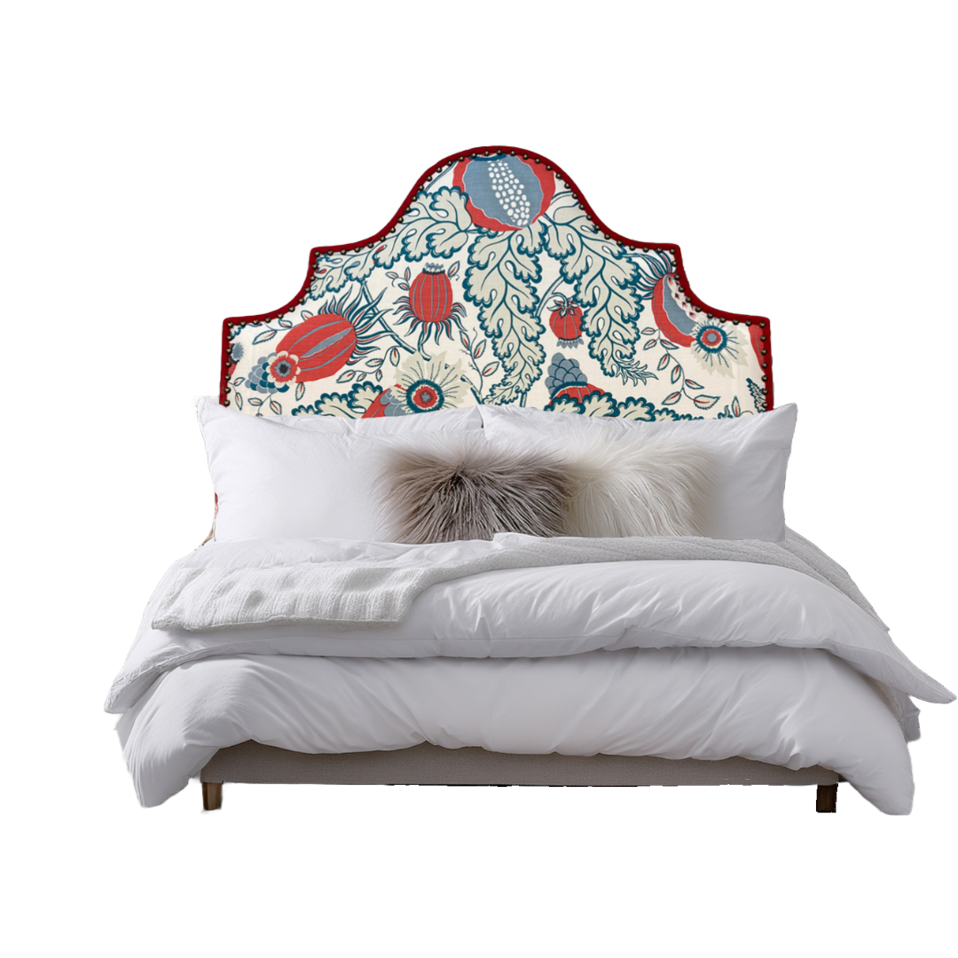 A bed with a colorful, ornate headboard featuring floral and fruit motifs, white bedding, and decorative pillows, including a faux fur pillow.