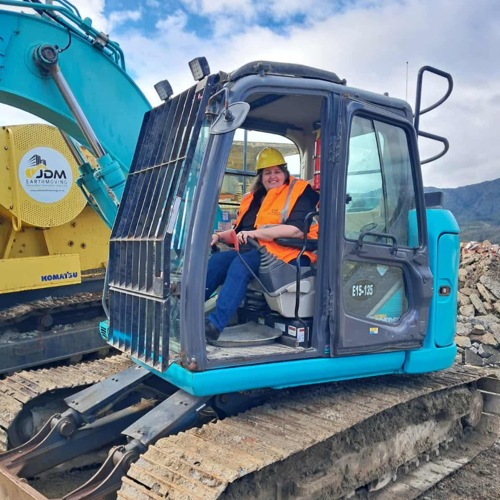 Angela in hi-vis vest driving a digger